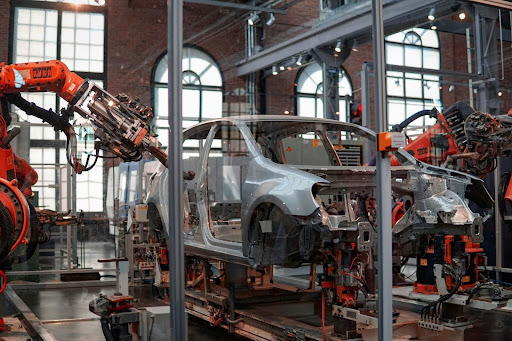 Industrial robots assembling a car body on an automotive manufacturing line, representing workplace safety, automation, and modern vehicle production.