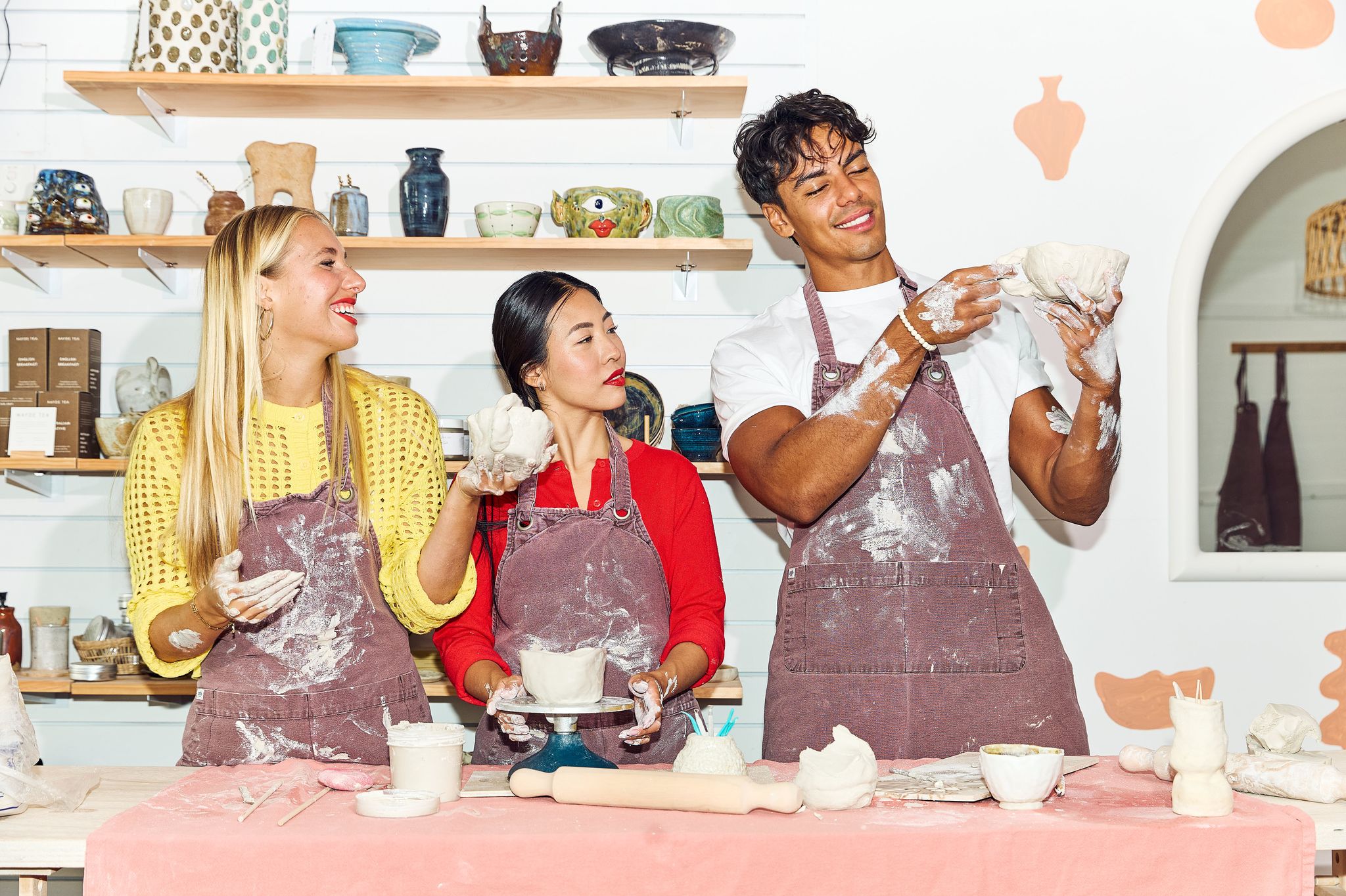 Three people making clay pots together in a pottery studio