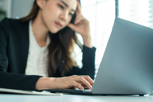 Professional woman concentrating while working on a laptop at a desk, representing cognitive focus, mental effort, and modern knowledge-based work.