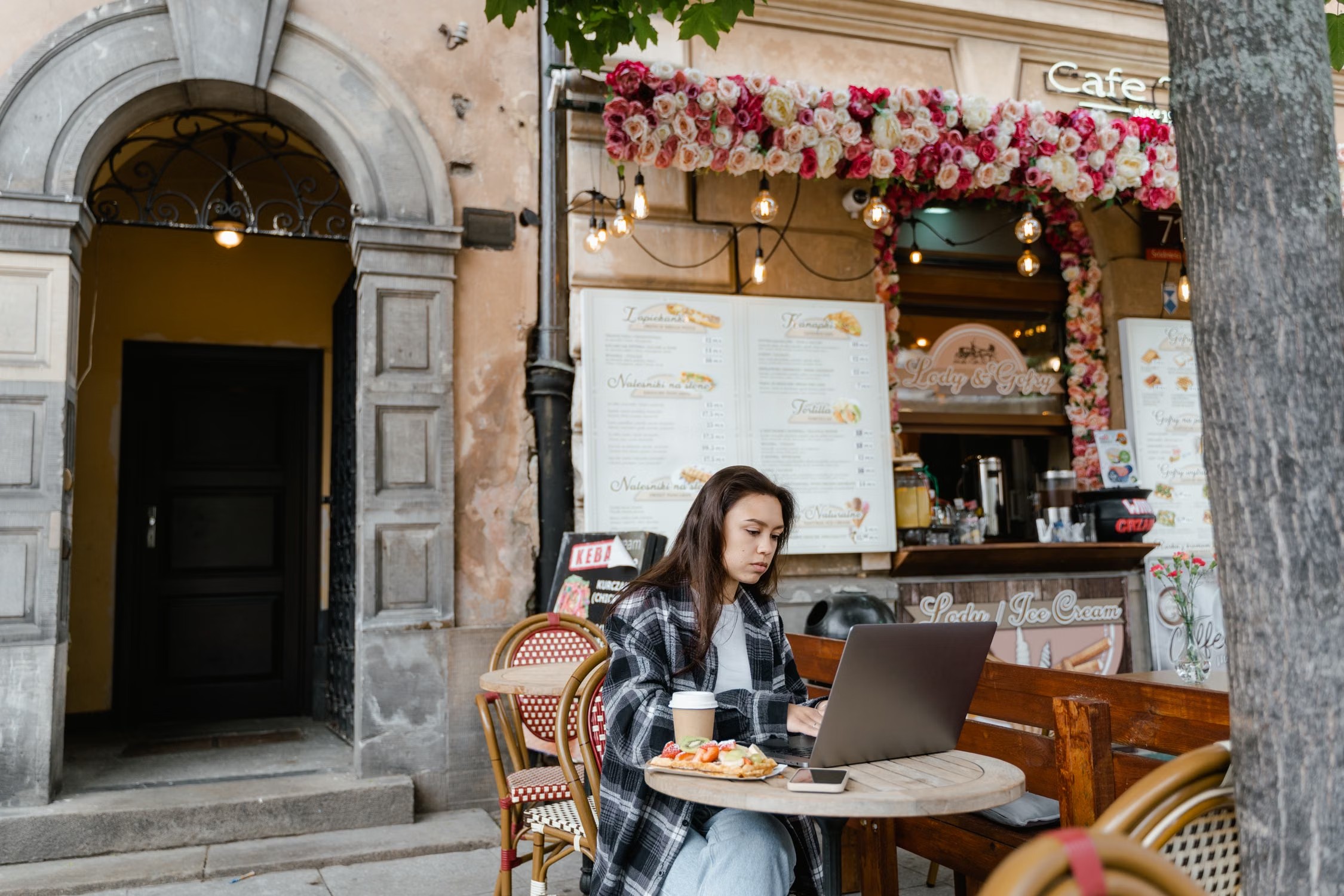 Woman working on a laptop at an outdoor café — photo by MART PRODUCTION, Pexels