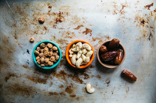 Small bowls of mixed nuts and dates arranged on a table, representing nutritious snacks for energy, focus, and balanced workplace nutrition.