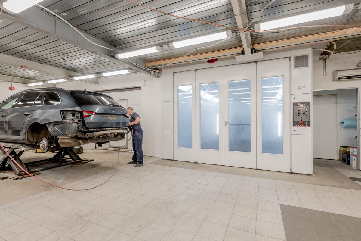 Mechanic working beside a raised car in an automotive repair workshop.