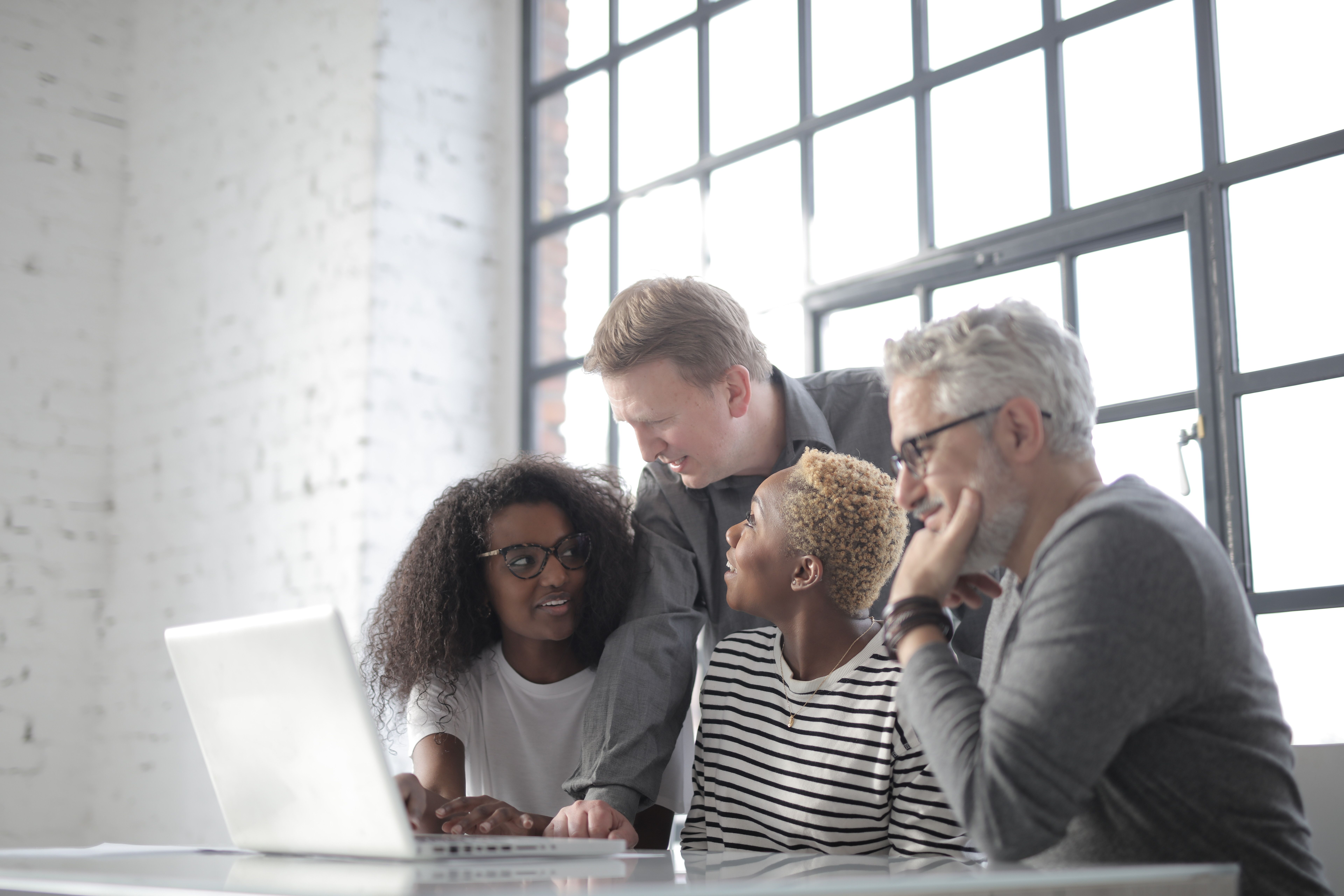 Colleagues working together around a laptop; illustrative stock photo