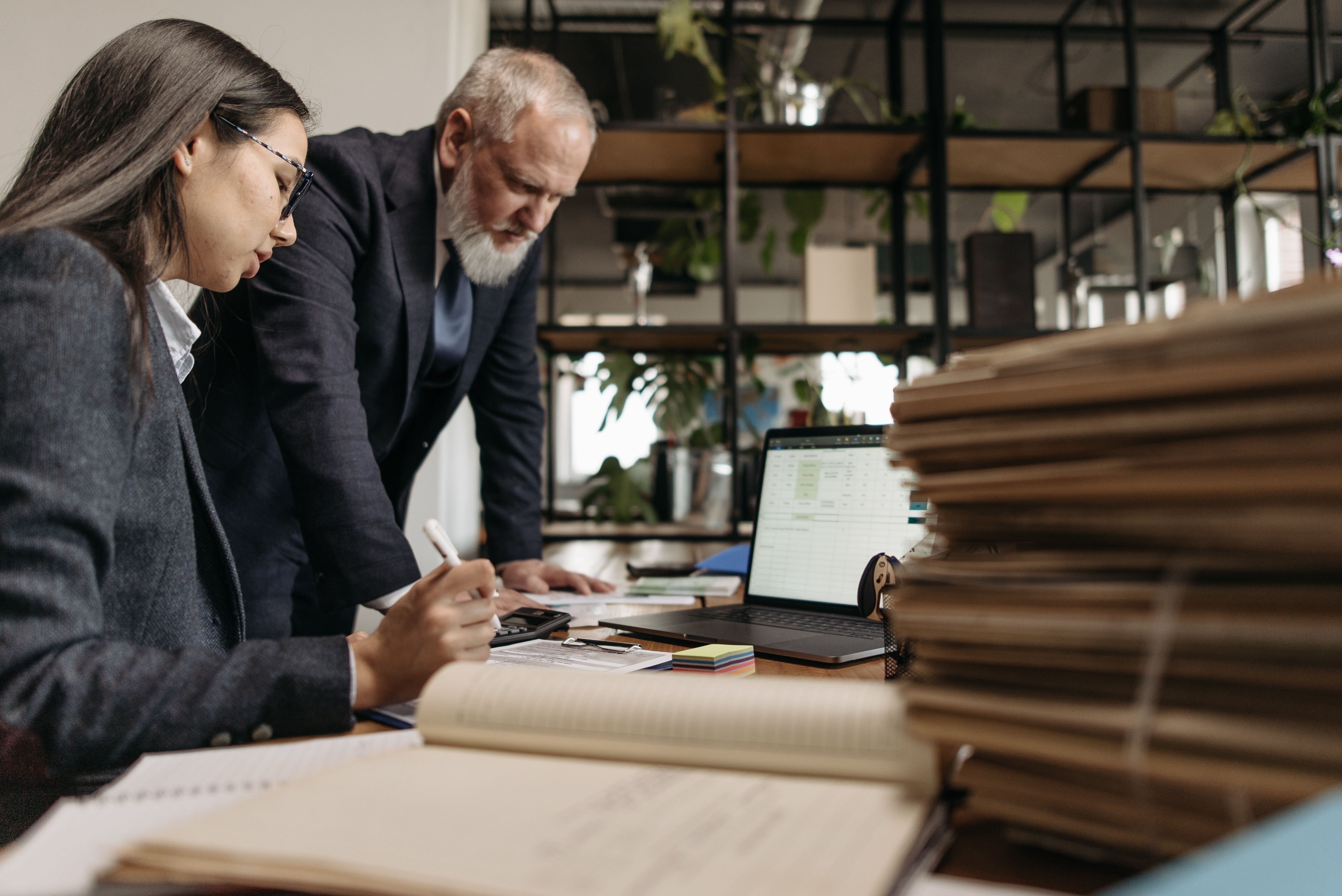 Office colleagues reviewing documents Two colleagues review documents together at an office desk