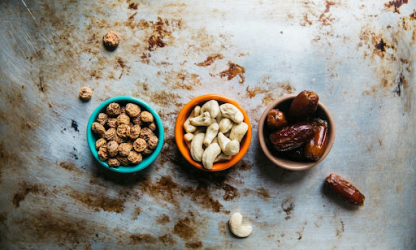 Small bowls of mixed nuts and dates arranged on a table, representing nutritious snacks for energy, focus, and balanced workplace nutrition.