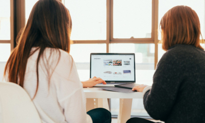 Two colleagues reviewing a laptop together at a desk — illustrative stock photograph.