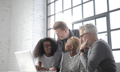 Colleagues working together around a laptop; illustrative stock photo