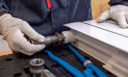 Plumber installing a radiator pipe using specialised tools