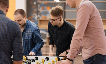 Coworkers playing table foosball together during a team-building activity in a modern office environment
