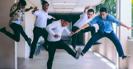 Energetic team bonding through playful movement at work Group of colleagues jumping and laughing together in a hallway, representing workplace energy, team bonding, and playful company culture