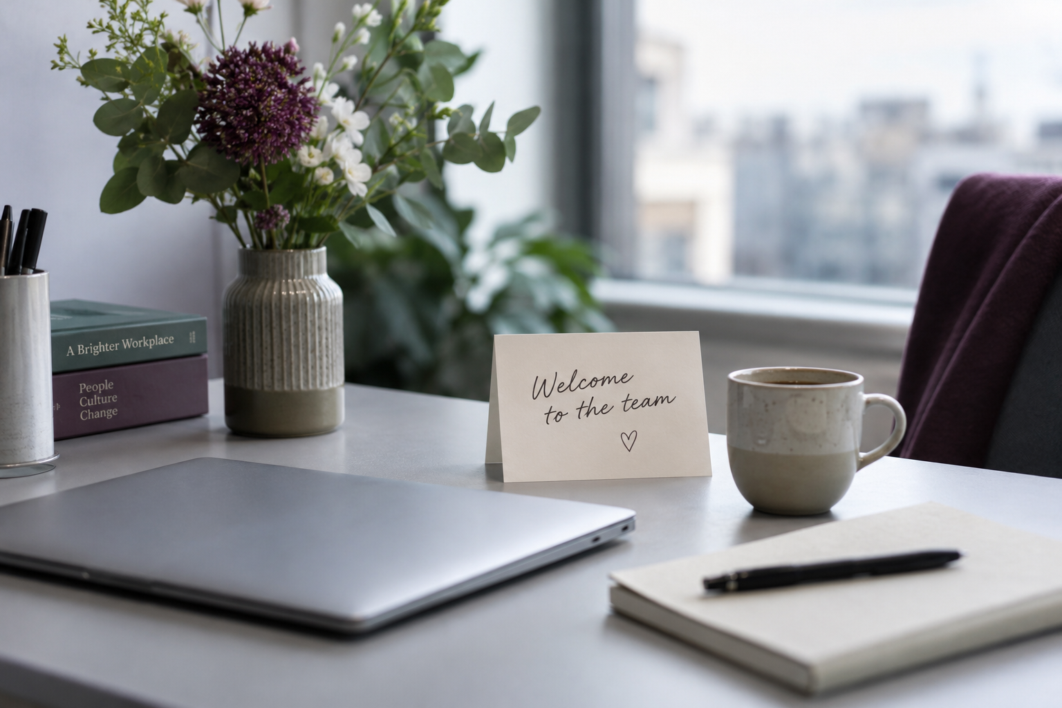 A prepared welcome desk with a laptop, notebook, coffee, flowers and a card saying Welcome to the team. Generated concept image.