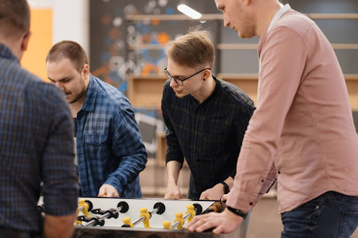 Coworkers playing table foosball together during a team-building activity in a modern office environment