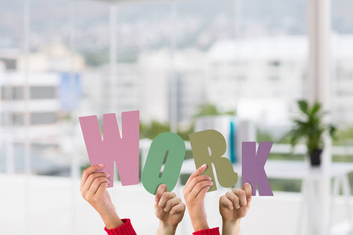 Employees holding colorful letters spelling “work,” symbolising teamwork and a positive workplace environment